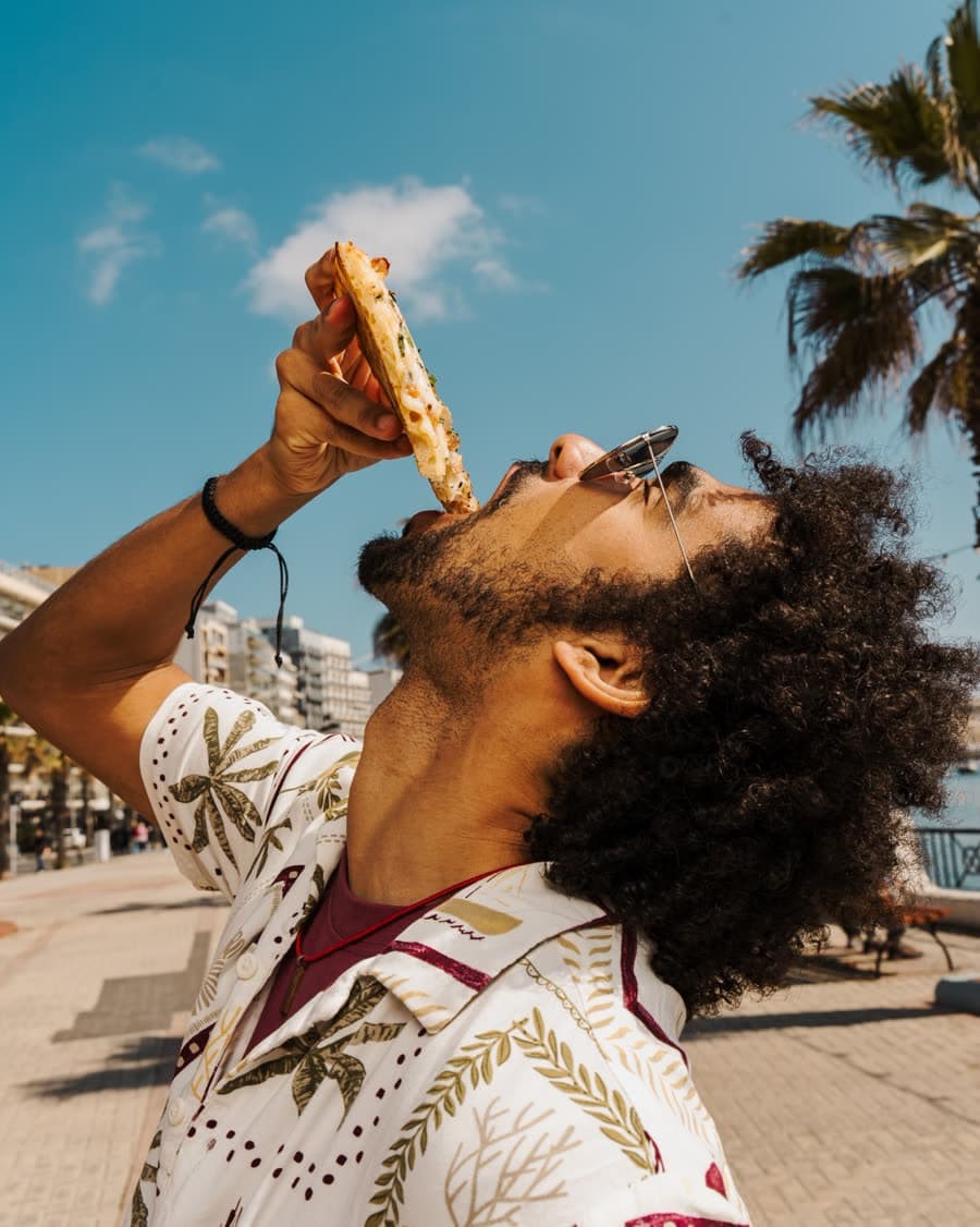 Eating a Steezza slice on the Gżira promenade under palm trees